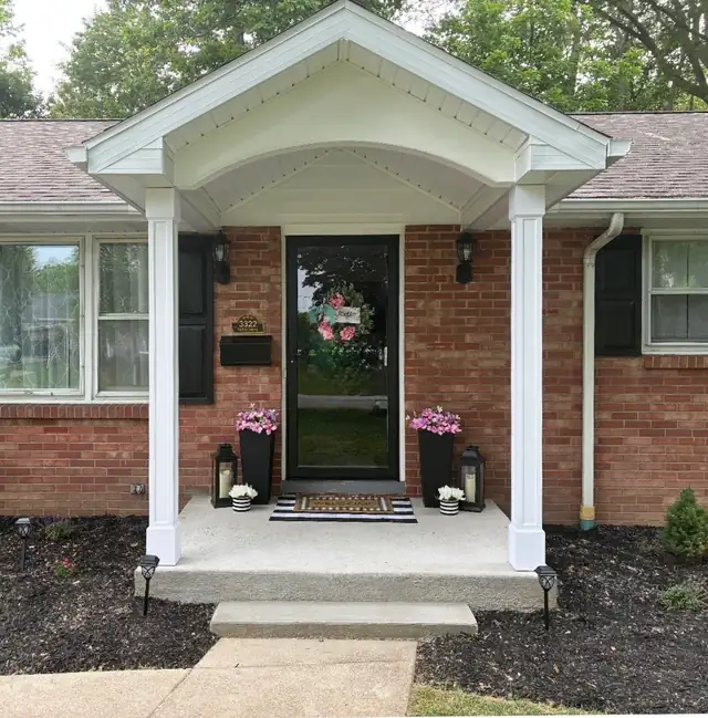 New white portico with gabled roof and columns over the front door of a brick ranch house